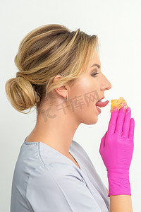 产品突出摄影照片_年轻的美容师舔液体蜡进行脱毛，手上戴着手套，站在白色背景上。