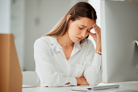 头痛动图摄影照片_一位焦虑的年轻西班牙裔女商人在办公室的电脑上工作时感到头痛。