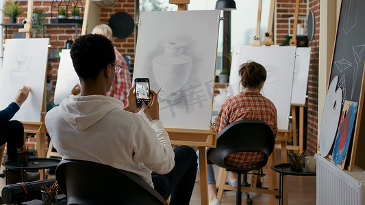 创意学生在智能手机上拍摄花瓶素描