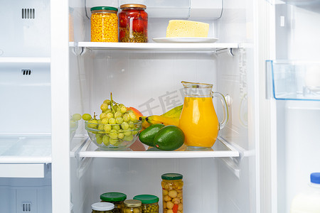 冰箱架上的橙汁和水果玻璃罐