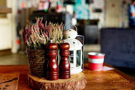 摇床摄影照片_咖啡馆里的木制传统盐罐和胡椒罐，有选择的焦点。乡村风格舒适室内的静物细节。木制香料罐，磨坊，餐厅餐桌设置的一部分。
