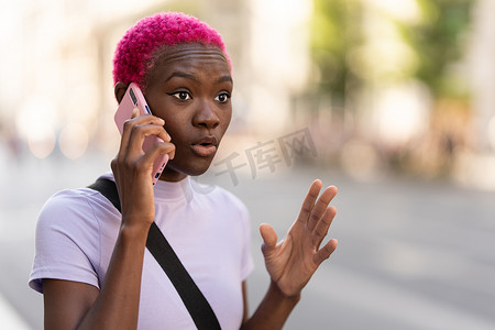 悲哀地摄影照片_年轻的非洲女性在户外用手机精力充沛地交谈