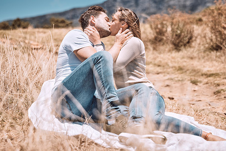 在阳光明媚的夏天或春天在户外野餐情人节约会接吻、相爱和年轻夫妇。