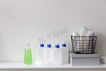 护发素摄影照片_浴室的架子上放着白色瓶子，上面有一个蓝色分配器，里面装有洗发水、护发素、面霜和液体肥皂。
