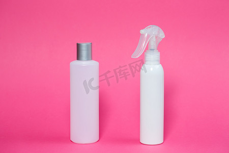 皮肤喷雾摄影照片_两个白色瓶子，里面有洗发水、身体凝胶、粉红色背景的皮肤喷雾