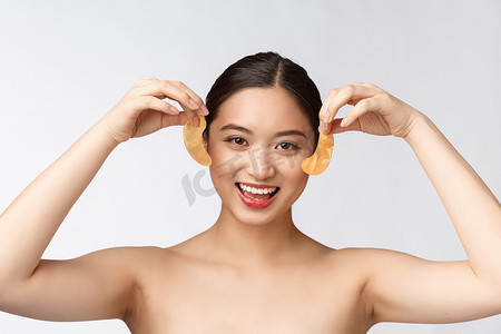 亚洲美女少女在眼睛下方用金色眼罩贴片护理皮肤