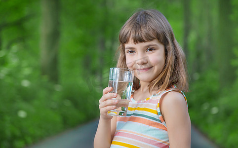 一个孩子在大自然中喝一杯水。