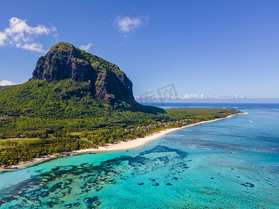 Le Morne 海滩毛里求斯，带棕榈树和白色沙滩蓝色海洋的热带海滩和带雨伞的沙滩床、太阳椅和遮阳伞在热带海滩的棕榈树下，Le Morne 海滩毛里求斯