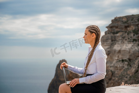 一个女人坐在露台上，在 macbook 键盘上打字，可以欣赏到美丽的海景。