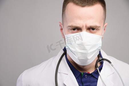 一位戴着防护口罩的年轻医生，表情严肃，阴沉地看着镜头。