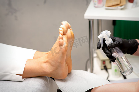 修脚师傅在美容院用准备去污的方法对妇女的脚进行消毒。