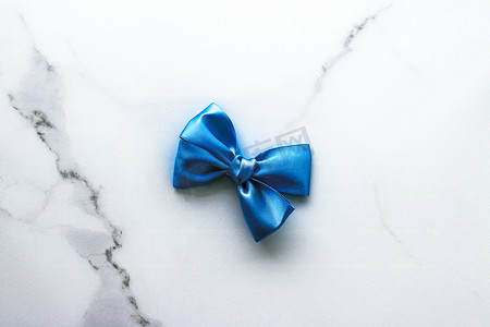 蓝色装饰彩带摄影照片_豪华大理石背景上的蓝色丝带和蝴蝶结、假日平底背景