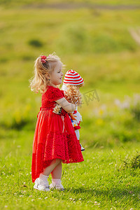 孩子大自然摄影照片_手里拿着洋娃娃的女孩站在大自然中