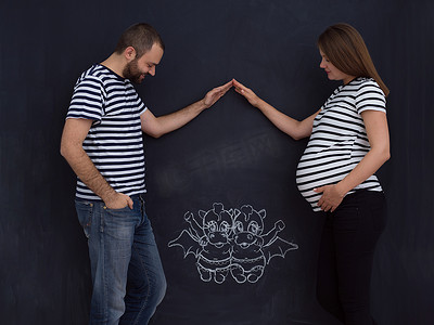 怀孕的夫妇在粉笔板上画出他们的想象力