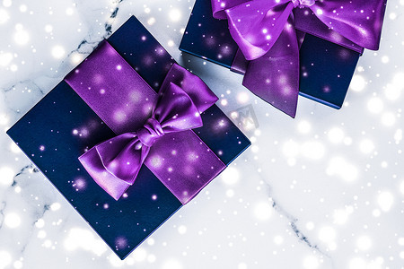 紫色的雪花摄影照片_带紫色丝弓的寒假礼盒，大理石背景上闪闪发光的雪花，作为豪华美容品牌的圣诞和新年礼物，平面设计