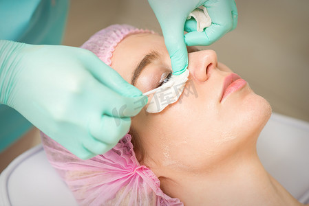 接受睫毛去除手术的年轻女性用棉签去除睫毛膏并贴在美容院。