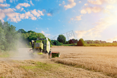 现代联合收割机在夏季收割小麦，背景是壮观的天空和彩虹。