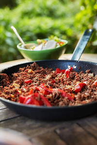 近距离观察热多汁的碎牛肉，用番茄酱、香料、罗勒和切碎的蔬菜在煎锅里炖，经典食谱。