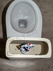厕所标语冲水摄影照片_白色马桶水箱，带有打开的盖子和冲水系统。