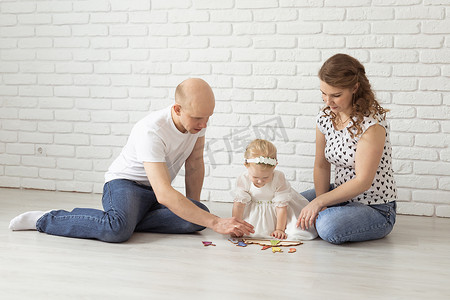 带助听器和人工耳蜗的婴儿与父母在地板上玩耍。