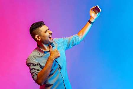 穿着衬衫的男人在视频通话中聊天，在手机上进行在线对话，竖起大拇指。