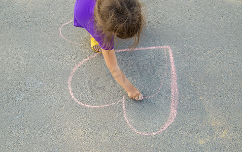 孩子在沥青心上涂粉笔。