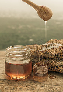 美味的蜂蜜从木制蜂蜜勺滴入新鲜的蜂窝中。