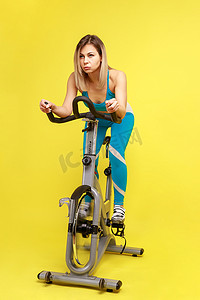 美丽的女人在健身自行车上进行有氧运动，减肥或改善体形。