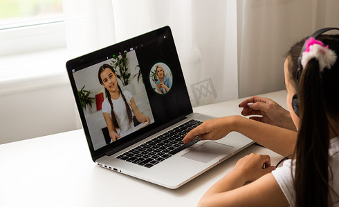 由于冠状病毒大流行，家庭学校的小女孩通过数字远程互联网会议向学校老师学习在线课程。