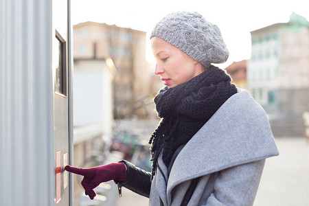 在寒冷的冬日，随便的女人在城市自动贩卖机上购买公共交通票。