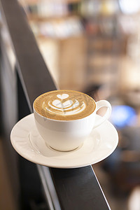 一杯带有拿铁艺术的卡布奇诺咖啡站在咖啡馆的背景上，散焦。