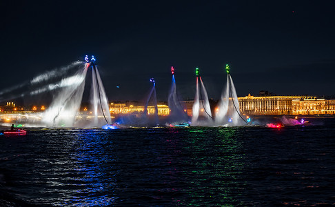 许多飞板手和穿着鲜艳的水上摩托艇运动员在圣彼得堡市中心的一个假期晚上表演他们的表演，进行水上活动