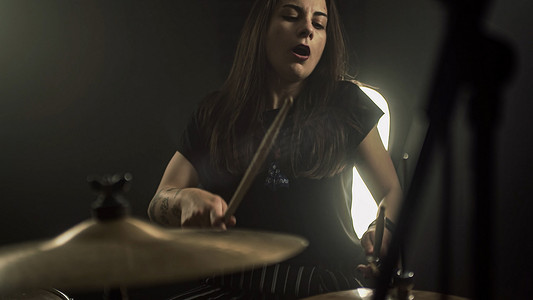 架子鼓摄影照片_一个精力充沛的女鼓手演奏架子鼓