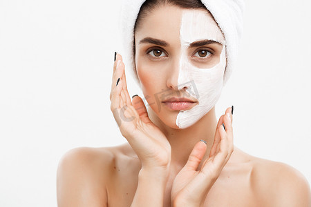 美容护肤概念-美丽的白种女人脸部肖像在她的面部皮肤白色背景上应用奶油面膜。