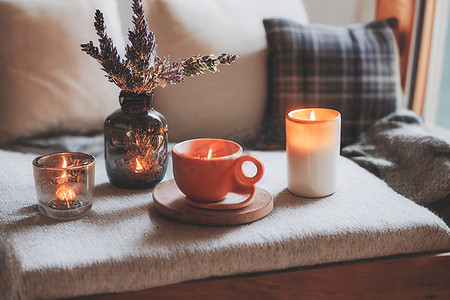 传统花纹摄影照片_秋季 hygge 家居装饰布置、hygge 和舒适的概念、燃烧的白色香烛