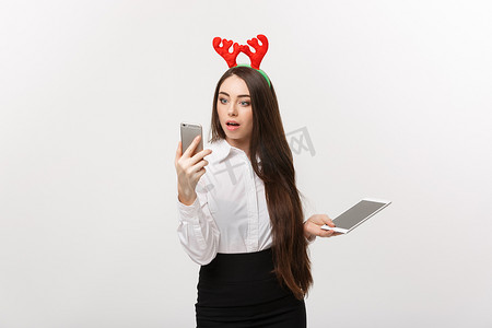 经营理念-圣诞主题中的年轻白人女商人用令人惊讶的面部表情玩移动电话。