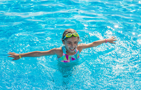 飞溅水花摄影照片_游泳池里的一个孩子溅起水花。