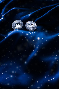深蓝色丝绸上的奢华钻石耳环，雪光闪闪，节日冬季魔法珠宝礼物