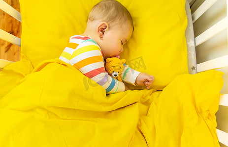 床上睡觉的婴儿摄影照片_婴儿在婴儿床上睡觉。