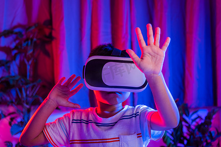 虚拟现实现实摄影照片_戴着虚拟现实护目镜体验现实的亚洲小男孩