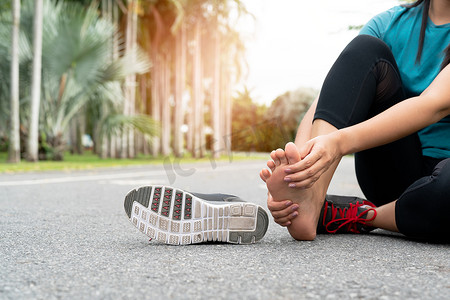 亚洲妇女在锻炼时按摩疼痛的脚。
