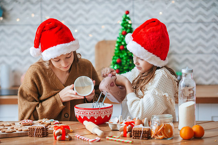 小女孩在装饰过的客厅的壁炉旁制作圣诞姜饼屋。