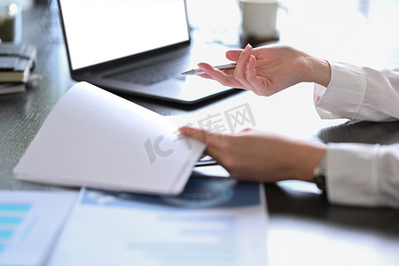 企业家剪影摄影照片_专业女商人使用笔记本电脑并在工作场所准备年度财务报告的剪影