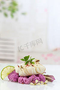 鳕鱼牛排蒸汽与浅色背景上的紫色椰菜花
