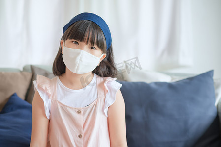 亚洲可爱的小女孩戴着卫生面罩以防止冠状病毒或 Covid-19 爆发，保持社交距离并呆在家里。