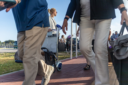 年轻女子用行李手推车将行李从到达停车场运送到国际机场出发航站楼。