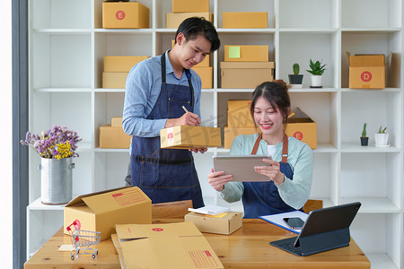 一家小型初创企业和中小企业主的肖像，一位亚洲男性和女性企业家为客户检查订单和包装，个体户，自由职业者，在线销售