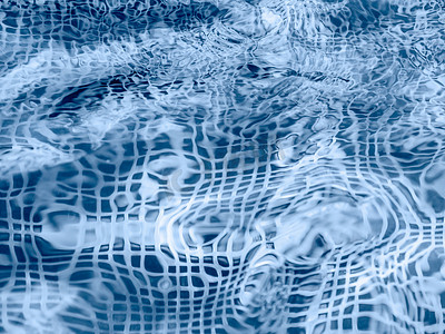 透明蓝色底摄影照片_带蓝色马赛克底的游泳池或喷泉的水面。