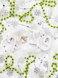 圣诞节和新年背景，配有 2019 年数字、绿色装饰、结婚戒指和灯泡。