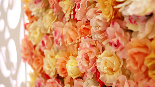 婚礼墙摄影照片_特写，婚礼装饰，玫瑰花蕾的节日装饰，美丽的橙色花蕾墙，桃玫瑰